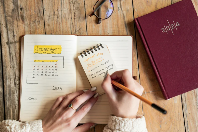 Person writing thoughts and tasks in a notebook